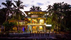 a large house with palm trees in front of it at Riverside Retreat in Kalyānpur