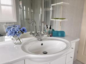 a white bathroom sink with a vase of blue flowers at Spacious Home for Workers & Families - Quiet area in Newton Aycliffe +26 photos