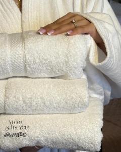 a woman is holding a stack of towels at Apandnrosm in Vlorë