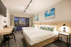 a hotel room with two beds and a desk at Nightcap at Kawana Waters Hotel in Kawana Waters