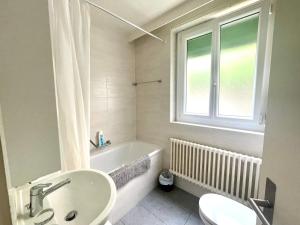 a bathroom with a sink and a tub and a window at 5 minutes à pied de la Gare in Lausanne