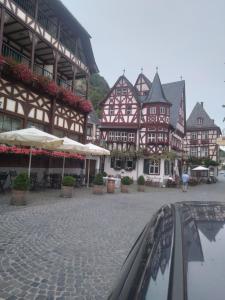 a group of brown and white buildings with tables and umbrellas at 100 Stufen über dem Rhein in Oberwesel