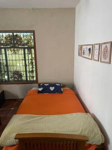 an orange bed in a room with a window at Lunas de Spilimbergo in Cordoba