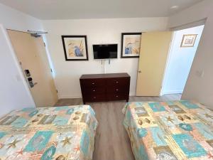 Un dormitorio con dos camas y un televisor en la pared. en Direct beach access 1st Floor walkout w/kitchen, en Daytona Beach 41 fotos más