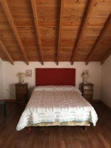 a bedroom with a bed with a red headboard and wooden ceilings at Villa Serena Deportista in Necochea