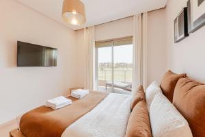 a bedroom with a bed with a couch and a tv at Luxury Appartement Golf and Pool in Marrakech +18 photos