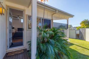 a house with a palm tree in front of a door at Delightful Dicky Beach Holiday House in Caloundra
