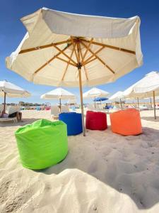 a group of chairs under an umbrella on the beach at شاليه بالساحل الشمالى قرية نيو كوست الكيلو 77 قبلى الطريق بشاطىء خاص in El Alamein +7 photos