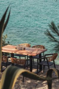 a wooden table and chairs next to the water at Villa Romantica Hotel in Paleo Tsifliki