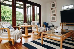 a living room with chairs and a flat screen tv at Family Beach House at Twin Waters Resort in Twin Waters +12 photos