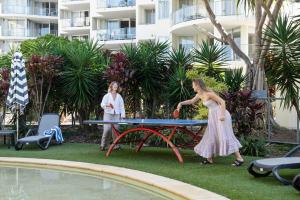due donne giocano a ping pong a un tavolo vicino a una piscina di Absolute Beachfront Marcoola - Private Pool - Private Spa Bath - Games a Marcoola