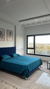 a bedroom with a blue bed and a large window at Villa de Campagne in Es Somaa