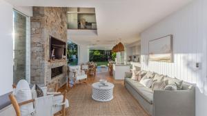 Coen by the Sea في ساحة كاسوارينا: غرفة معيشة مع أريكة ومدفأة حجرية