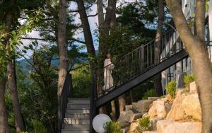 a woman standing on a staircase in front of a house at Gyeongju Forest 258 Pet-friendly Pool Villa in Gyeongju