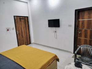 AyodhyaHotel Paramount Inn的一间卧室，墙上有一张床和一台电视