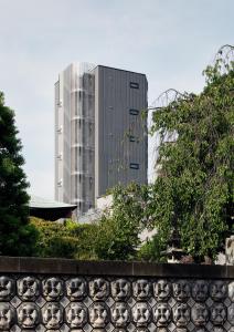a tall building in the background with a fence at FL Hotel Asakusa in Tokyo