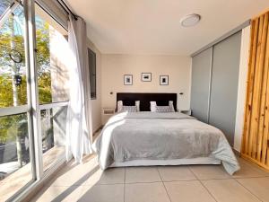 a bedroom with a bed and a large window at Studio Conexión Mendoza moderno céntrico Wifi alta velocidad y a pasos del Parque Gral San Martín y Aristides Villanueva in Godoy Cruz