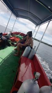 Una mujer sentada en un barco hablando por un teléfono celular en Famili Dive Shop, 