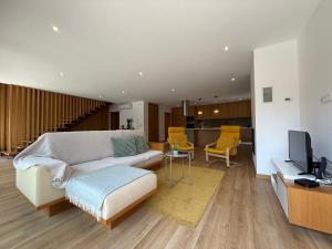 a living room with a white couch and a television at Casa da Fonte - Gerês in Terras de Bouro
