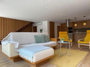 a living room with a white couch and yellow chairs at Casa da Fonte - Gerês in Terras de Bouro
