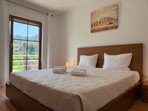 a bedroom with a large bed with a large window at Casa Terra Nova - Gerês in Terras de Bouro +47 photos