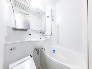 a white bathroom with a tub and a sink at APA Hotel Hakata Higashihieekimae in Fukuoka
