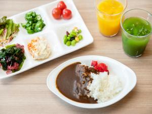 a table with two plates of food and two glasses of orange juice at APA Hotel Hakata Higashihieekimae in Fukuoka +37 photos