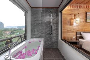 a bathroom with a bath tub and a bedroom at Tam Coc Orchid Hotel & Spa in Ninh Binh +75 photos