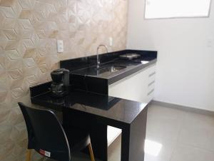 a black and white kitchen with a sink and a chair at aeroporto e praia loft estiloso in Vitória