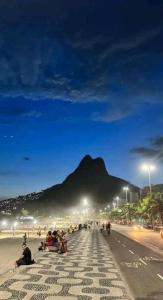 a group of people sitting on a sidewalk at night at Casa de casal in Duque de Caxias