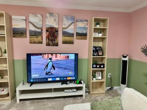 a living room with a television and a penguin on the screen at Stylish Studio with Kitchenette in Sterling