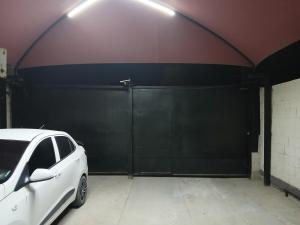 ein weißes Auto in einer Garage mit einem schwarzen Tor geparkt in der Unterkunft Departamento chico para tu estancia en ciudad juarez in Zaragoza