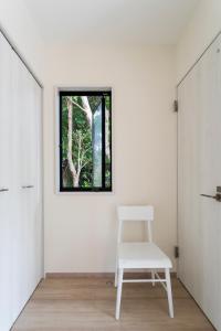 a white chair in a room with a window at Machicanty -まちかんてぃ- in Motobu