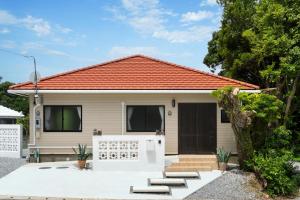 a small white house with an orange roof at Machicanty -まちかんてぃ- in Motobu