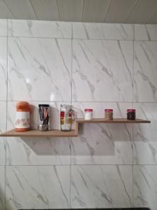 a shelf on a white tiled wall with spices at Kitnet Perto de Tudo-Varanda-Garagem in Feira de Santana +13 photos