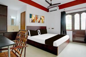 Un dormitorio con una cama, una mesa y una silla. en Hotel O Premier Park, en Trivandrum