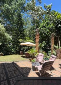 a patio with two chairs and an umbrella at Casa ROMERO EN FLOR in Medellín