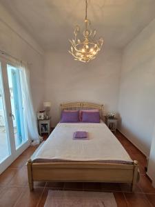 a bedroom with a large bed and a chandelier at Phaedra Villa Kythnos in Kithnos