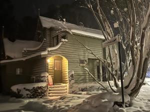 a house with a lighted door in the snow at Bindi - Alpine Getaways's Chalet at Tower Rd in Dinner Plain