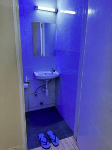 a bathroom with a sink and a mirror and slippers at The Skyline Loft in Juja