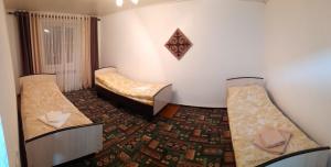 a room with two beds and a rug at Kyrgyz Family in Bokonbayevo