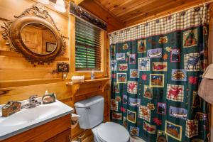 een badkamer met een toilet, een wastafel en een spiegel bij Peaceful Pines Cabin-patio with hot tub for small families or couples in Gatlinburg +38 foto's