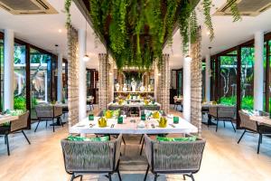 a restaurant with tables and chairs and plants at The Sarojin in Khao Lak