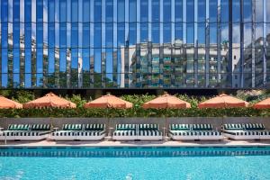 a pool with chairs and umbrellas in front of a building at The Standard, Singapore in Singapore
