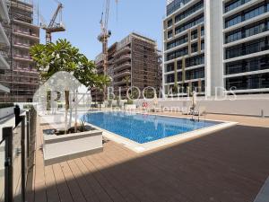 Bloomfields Deluxe Studio In Azizi Riviera في دبي: حمام سباحة في مدينة ذات مبانٍ شاهقة