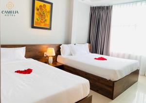 two beds in a hotel room with red flowers on them at Camelia 108 Le Lai Hotel in Ho Chi Minh City +16 photos