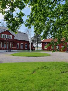 a large red building with a green field and trees at Hova Prästgård Bed & Breakfast in Hova
