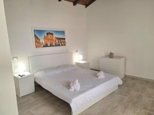 a white bedroom with a bed and two night stands at Nata Sicula 3 in Siracusa