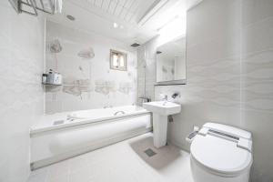 a white bathroom with a toilet and a sink at Zenith Hotel in Guri +51 photos
