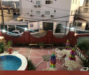 eine Terrasse mit einem Pool, Stühlen und Sonnenschirmen in der Unterkunft Hotel Las Flores in Acapulco